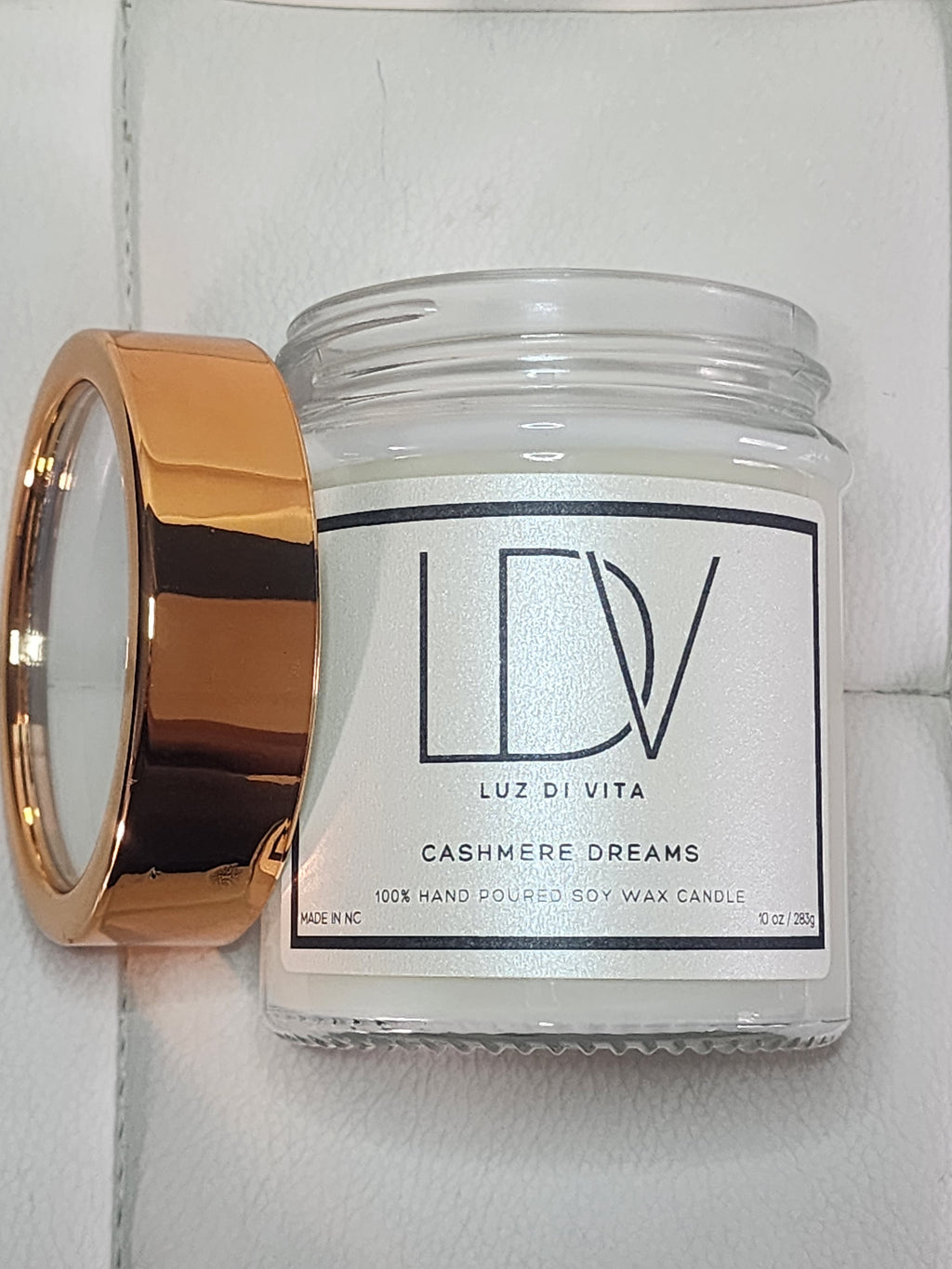 Candle with a gold holder and visible brand label on a white background. Christian prayer candle in a cozy home setting.