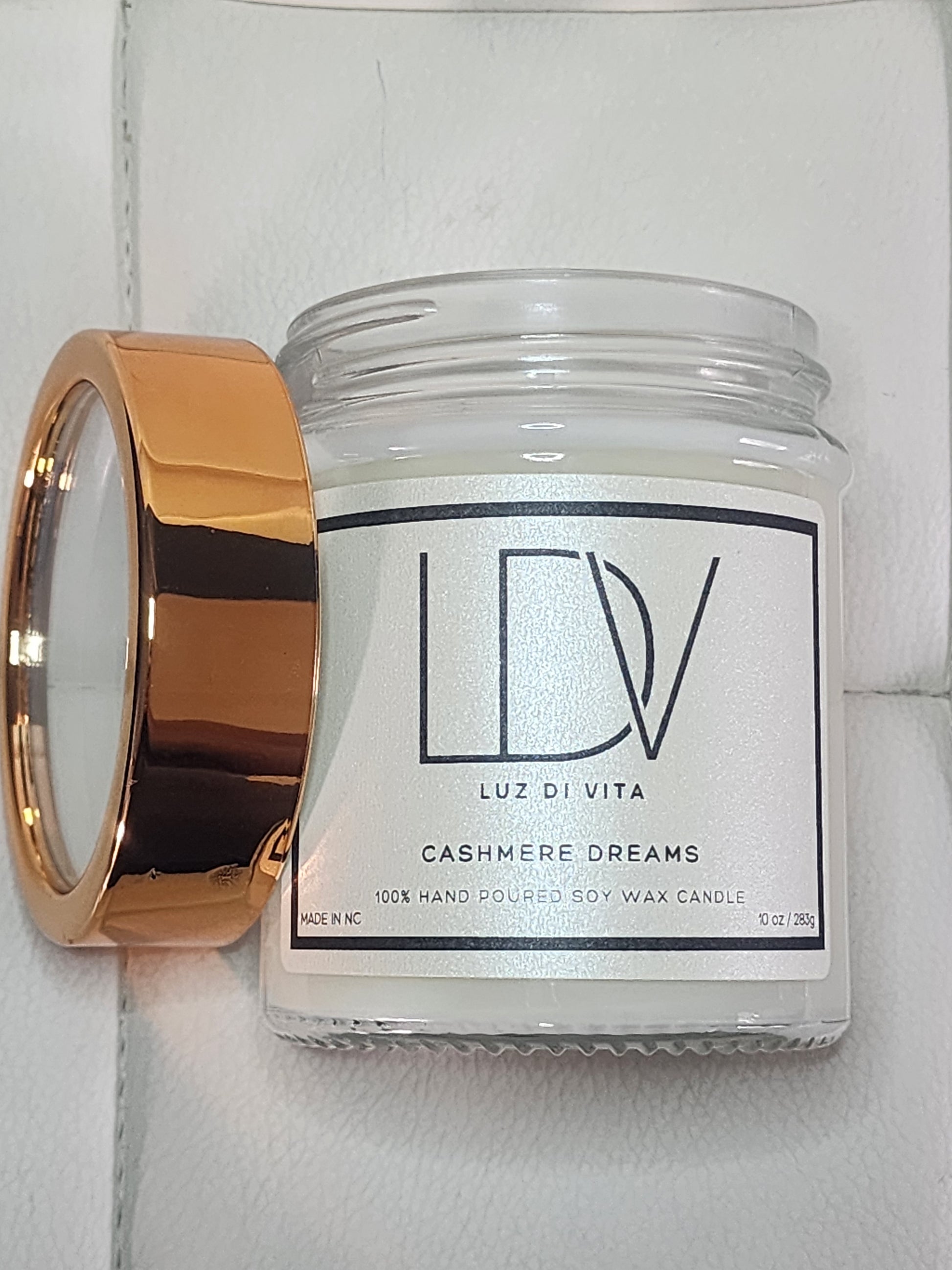 Candle with a gold holder and visible brand label on a white background. Christian prayer candle in a cozy home setting.